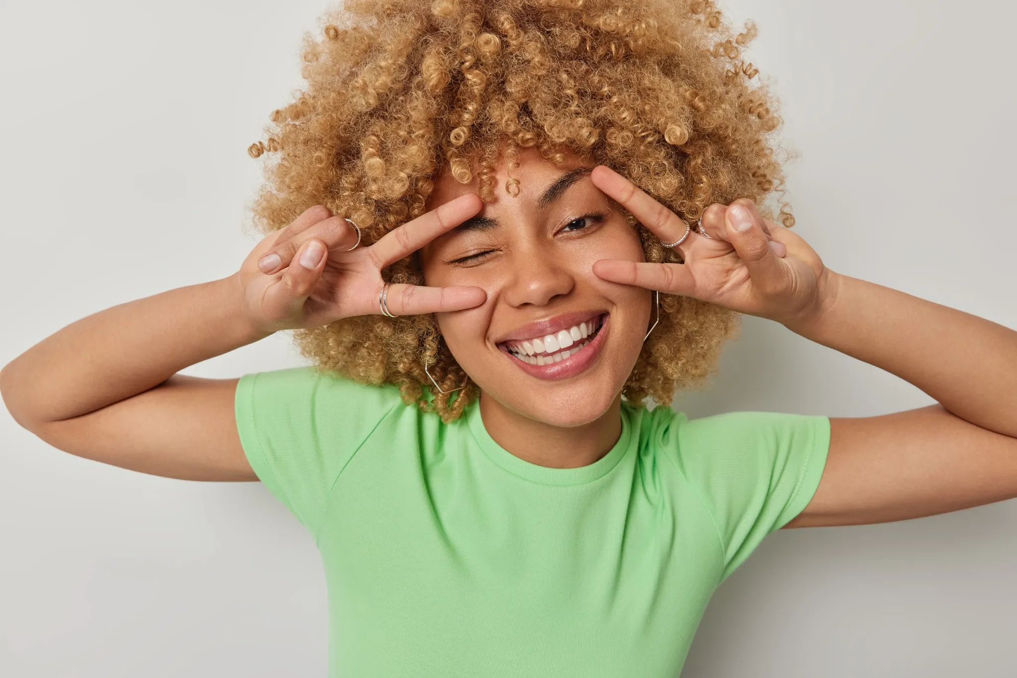 Blog 19 Young woman flashing a bright, carefree smile with a peace gesture – perfect dental care representation