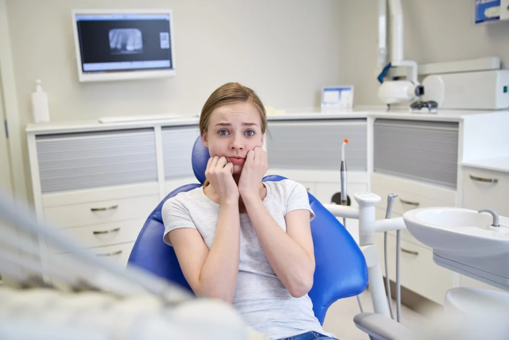 Nervous girl sitting in a dental chair, showing the risks of skipping dental visits in Fresno