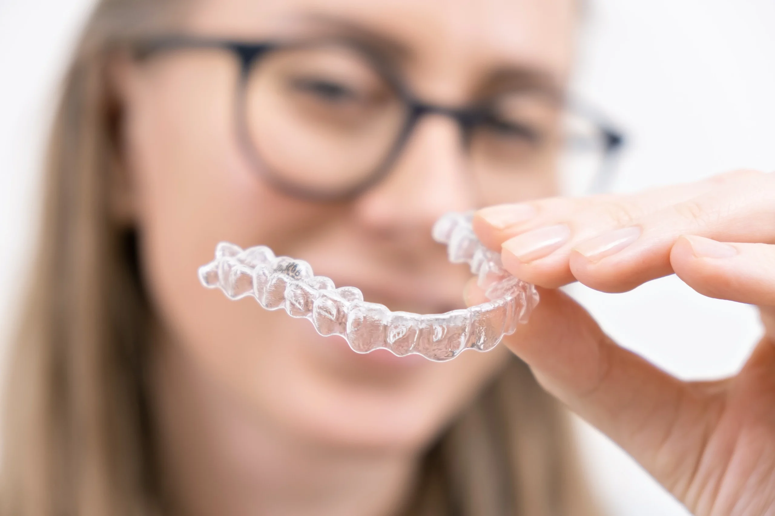 smiling woman using clear plastic removable braces aligner whitening tray dental orthodontic care scaled
