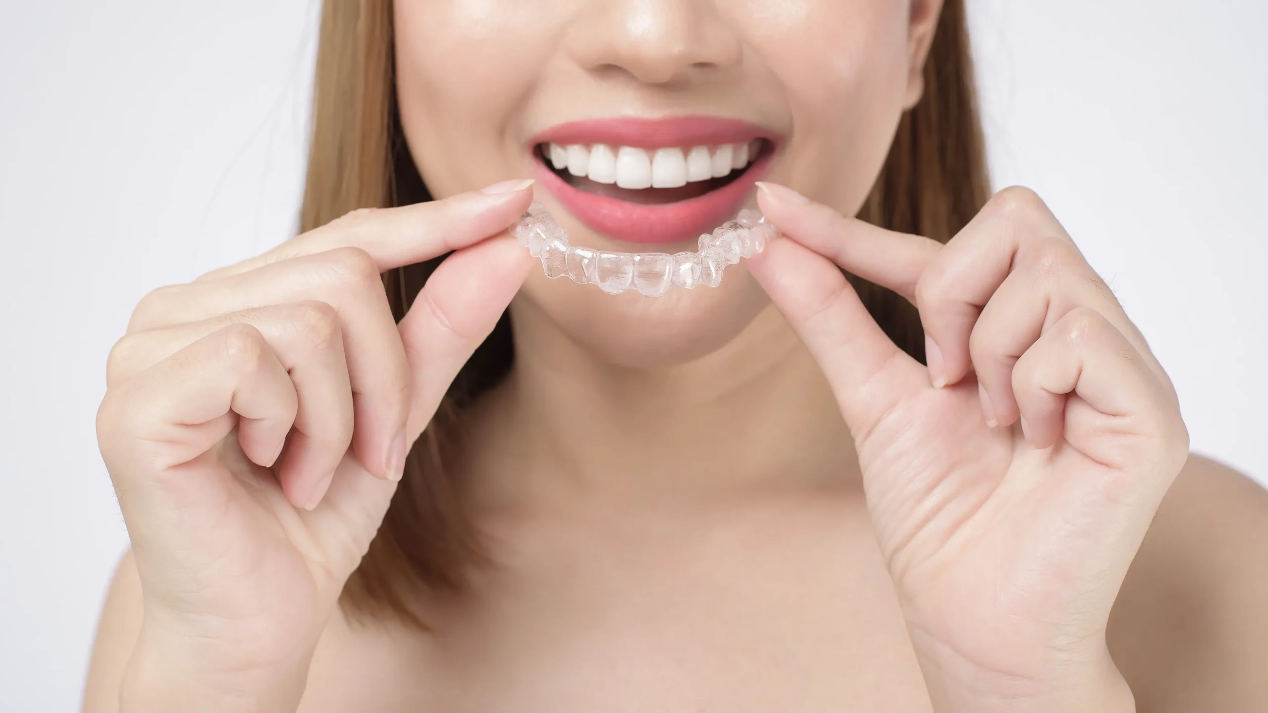 young smiling woman holding invisalign braces studio dental healthcare orthodontic concept scaled